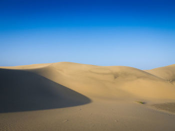 Scenic view of desert against clear blue sky