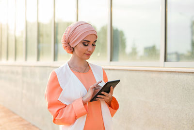 Young woman looking away while standing on mobile phone