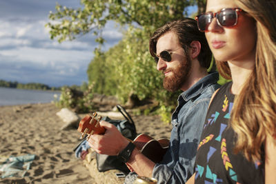 Woman sitting with friend playing ukulele