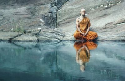 Reflection of monk meditating on lake