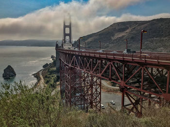 Bridge over sea against cloudy sky