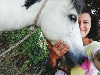 Smiling woman with white horse at farm