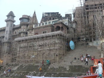 People at historic building in city against sky