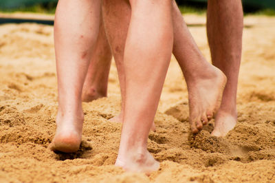 Low section of men playing on sand at beach