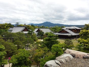 Houses by trees and buildings against sky