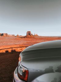 Car on desert land against clear sky