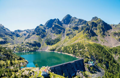 Scenic view of lake and mountains against clear blue sky