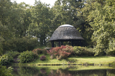 Gazebo by lake in forest against sky