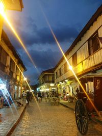 People on street amidst buildings in city at night