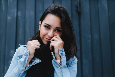 Portrait of young woman standing against wall