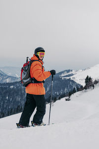 Skier with ski pole walking on snow