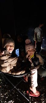 Rear view of smiling boy with arms outstretched at night