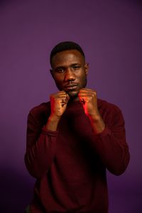 Portrait of young man standing against colored background