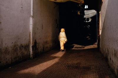 Rear view of woman walking on footpath amidst buildings