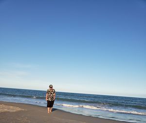 Man standing on beach against clear sky