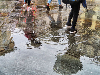 Low section of people walking on wet street during rainy season