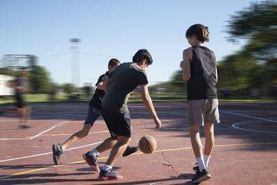 Group of teenagers playing street basketball