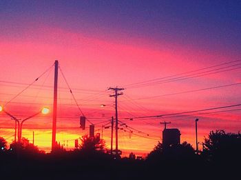 Low angle view of electricity pylon at sunset