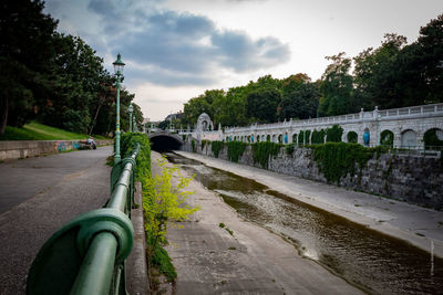 Road by bridge in city against sky