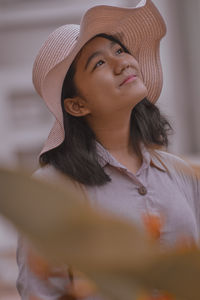 Close-up portrait of a young girl wearing a hat looking up to the sky 