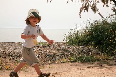 Full length of boy standing on beach against sky