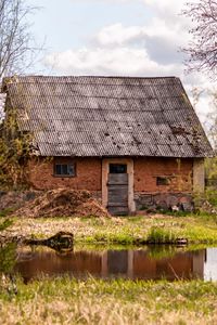 Old house made it clay near water against sky