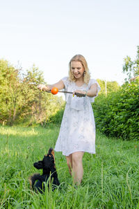 Portrait of smiling woman with dog on field