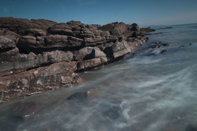 Scenic view of rocks in sea against sky