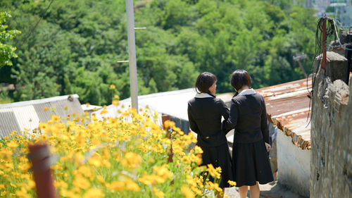 Rear view of people standing by flower plants