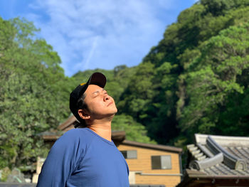 Portrait of young man standing against trees