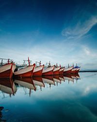 Boats moored in lake against blue sky