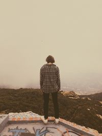 Rear view of man standing on street against sky