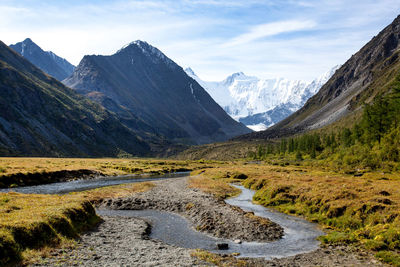 Scenic view of stream by mountains against sky