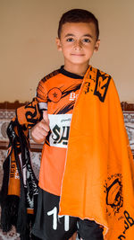 Portrait of smiling boy standing against orange wall