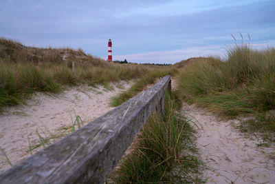 Road leading towards lighthouse amidst plants against sky