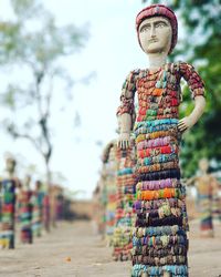 Close-up of decorated statues on field against trees and sky