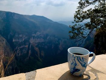 Coffee cup on table against mountains