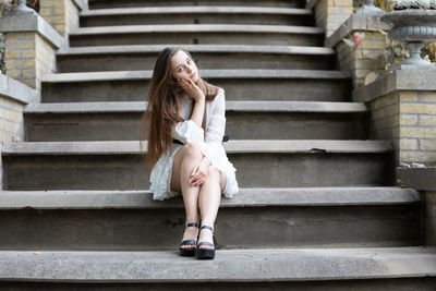 Full length of young woman sitting on staircase