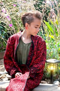 Young woman looking down while sitting by plants