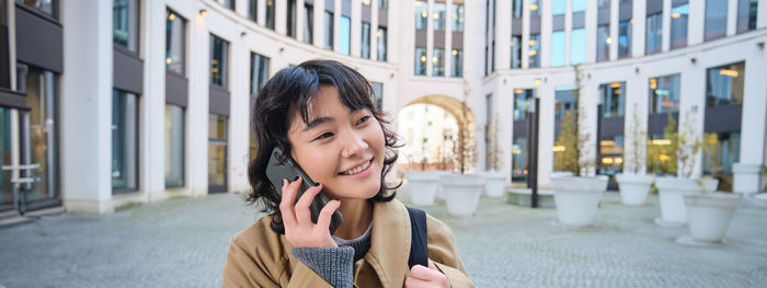 Portrait of young woman standing in city