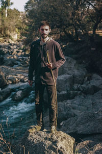 Portrait of young man standing on rock at forest