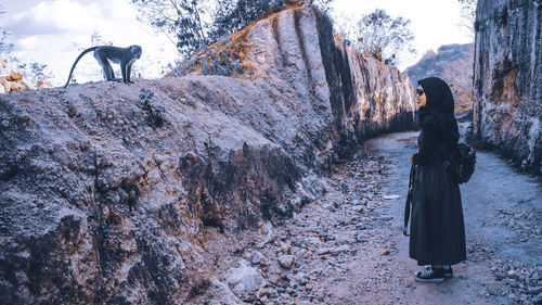 Rear view of woman standing on rock