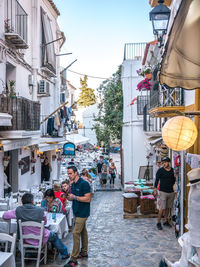 People sitting on street against buildings in city