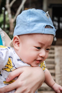 Cropped hand holding baby girl looking away