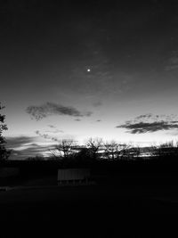 Silhouette trees on field against sky at dusk