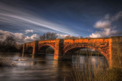 Arch bridge over river against sky