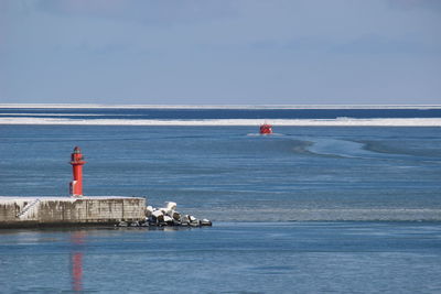 Lighthouse by sea against sky