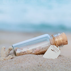 Close-up of bottle with wedding ceremony label on sand at beach
