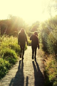 Rear view of sibling walking footpath against sky