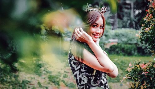 Portrait of smiling young woman standing against plants